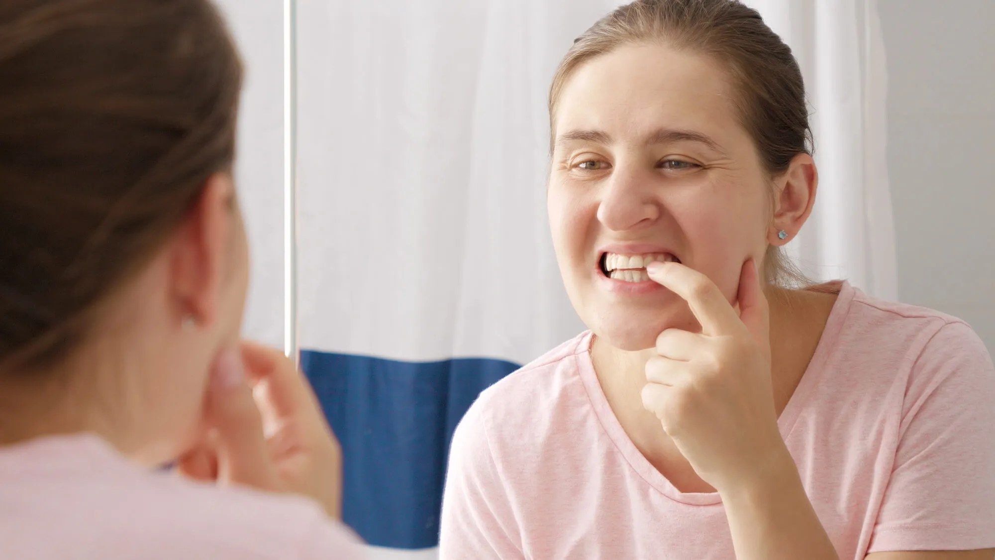 woman-checking-her-teeth-in-the-mirror-needs-to-see-a-dentist-miami